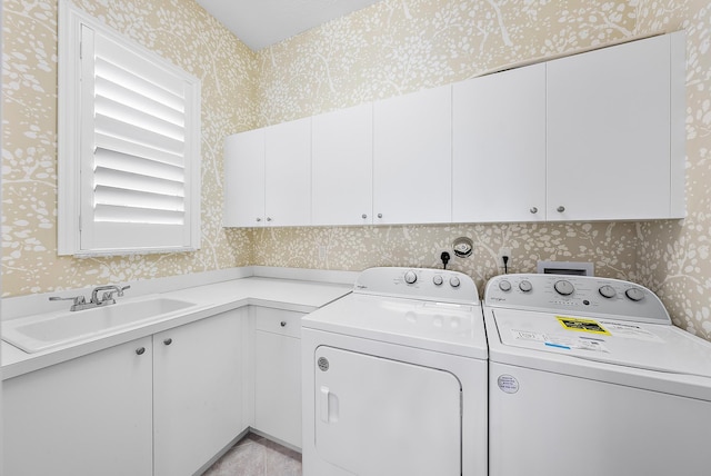 clothes washing area featuring washing machine and dryer, sink, and cabinets