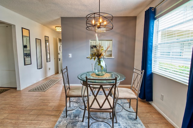 dining space featuring an inviting chandelier, plenty of natural light, and light wood-type flooring