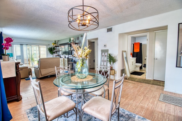 dining area featuring a textured ceiling, an inviting chandelier, and light hardwood / wood-style flooring