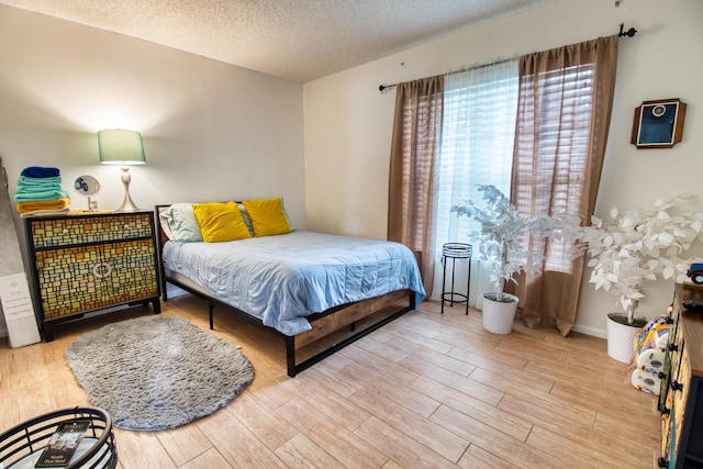 bedroom with light wood-type flooring and a textured ceiling