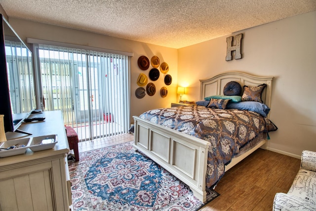 bedroom featuring hardwood / wood-style floors, access to outside, and a textured ceiling