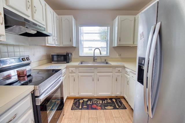 kitchen featuring stainless steel appliances, white cabinetry, sink, and light wood-type flooring