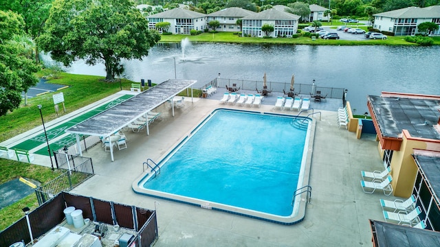 view of swimming pool with a patio, a water view, and a lawn