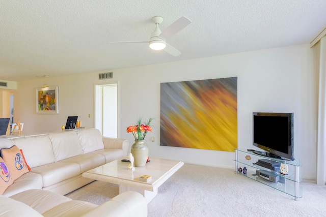 carpeted living room with ceiling fan and a textured ceiling