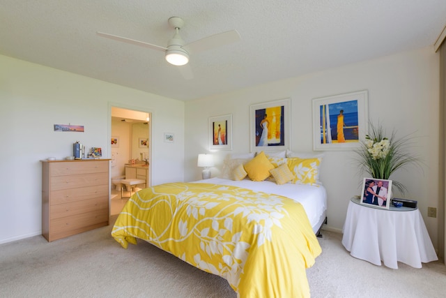 bedroom with ceiling fan, ensuite bath, light carpet, and a textured ceiling