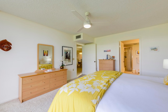 carpeted bedroom with ceiling fan, ensuite bath, and a textured ceiling