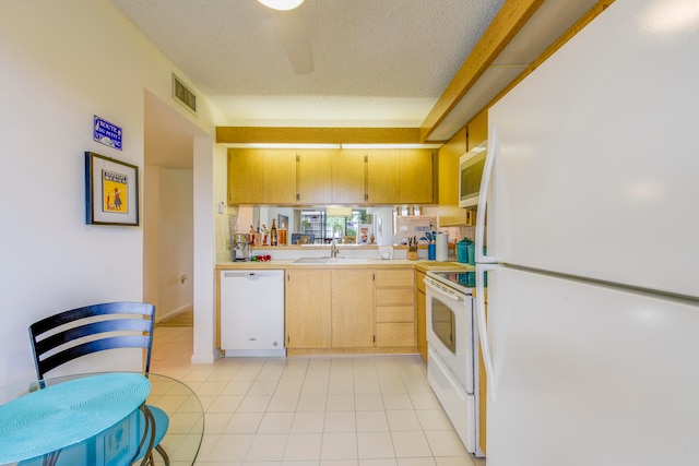 kitchen with sink, white appliances, light tile patterned floors, and a textured ceiling