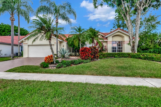 view of front of home featuring central air condition unit, a front lawn, and a garage