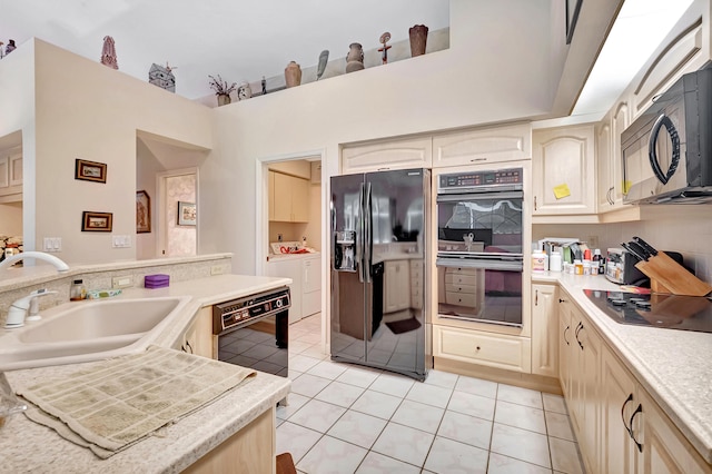 kitchen featuring black appliances, washer and dryer, light tile patterned floors, and sink