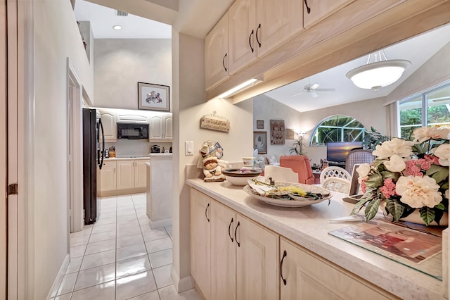 kitchen with light brown cabinetry, ceiling fan, black appliances, light tile patterned floors, and lofted ceiling