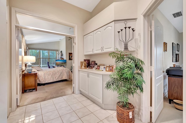 interior space with white cabinets, light colored carpet, and vaulted ceiling