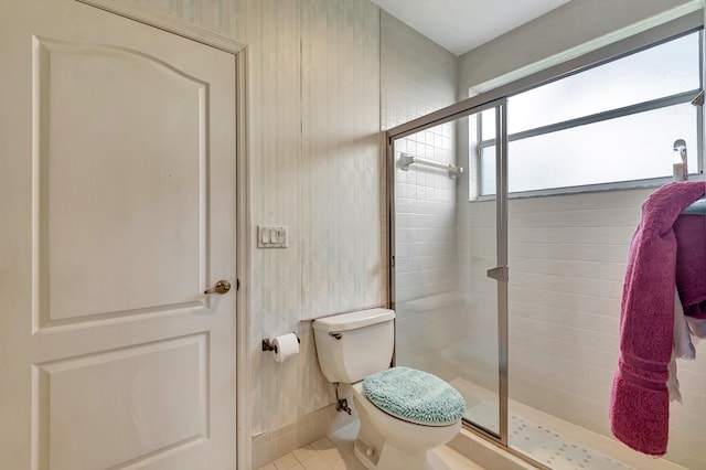 bathroom featuring toilet, tile patterned floors, a shower with door, and a healthy amount of sunlight