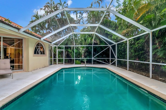 view of pool with glass enclosure and a patio area