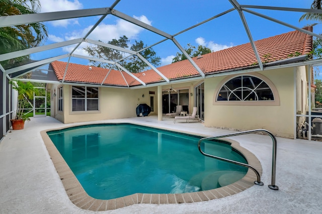 view of swimming pool with glass enclosure, ceiling fan, and a patio