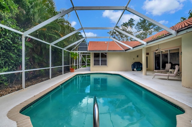 view of pool with glass enclosure, ceiling fan, and a patio area