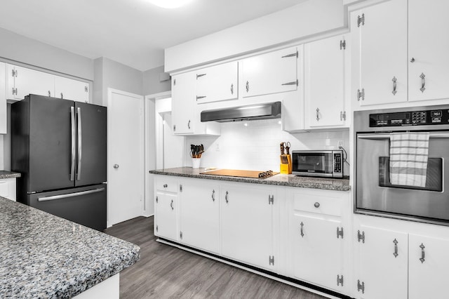 kitchen featuring dark wood-type flooring, white cabinets, extractor fan, appliances with stainless steel finishes, and dark stone countertops