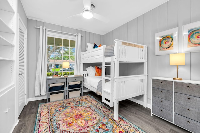 bedroom featuring wood walls, ceiling fan, and dark hardwood / wood-style floors