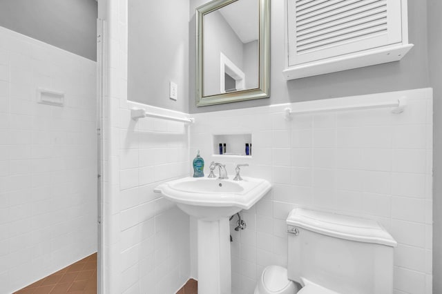 bathroom featuring toilet and tile walls