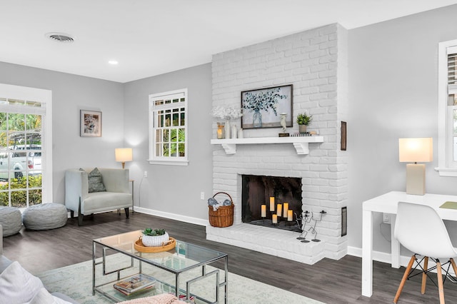 living room featuring dark hardwood / wood-style floors and a brick fireplace