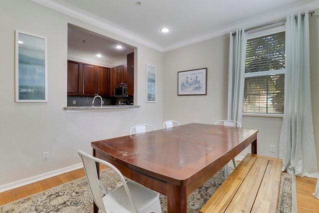 dining room featuring ornamental molding, light hardwood / wood-style flooring, and sink