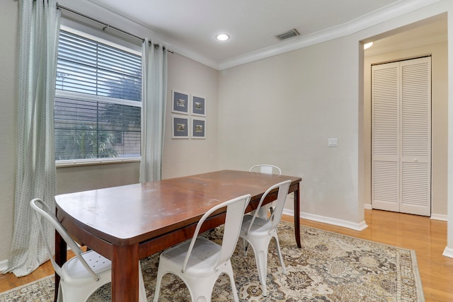 dining room featuring light wood-type flooring and crown molding