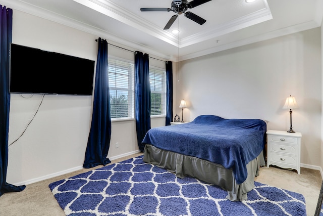 carpeted bedroom with ornamental molding, ceiling fan, and a raised ceiling