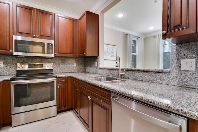 kitchen featuring sink, light stone counters, appliances with stainless steel finishes, ornamental molding, and backsplash