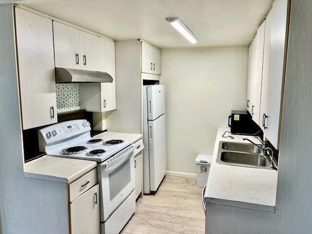 kitchen with sink, white appliances, white cabinetry, and light wood-type flooring