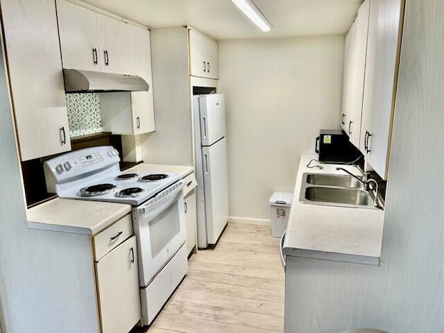 kitchen featuring sink, white appliances, white cabinets, and light hardwood / wood-style flooring