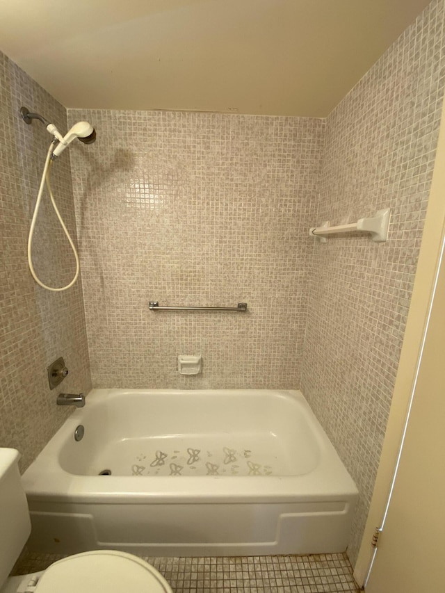 bathroom featuring tile patterned flooring, toilet, and tiled shower / bath