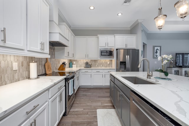 kitchen with white cabinetry, sink, stainless steel appliances, crown molding, and pendant lighting