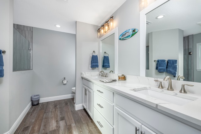 bathroom with hardwood / wood-style floors, vanity, toilet, and walk in shower