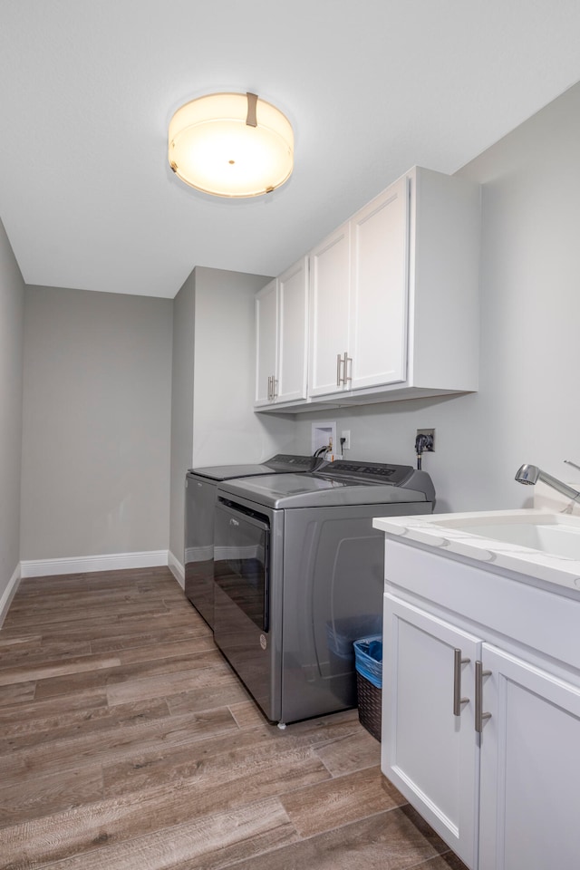 laundry room with cabinets, light wood-type flooring, and washer and clothes dryer