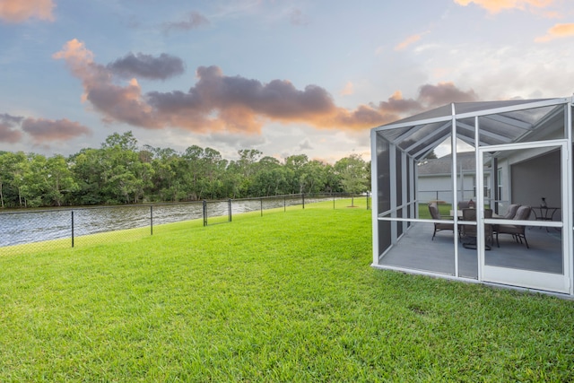 yard at dusk with glass enclosure and a water view