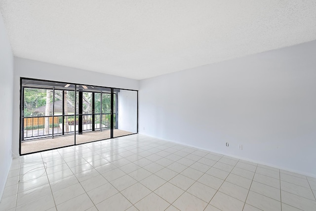 spare room with a textured ceiling and light tile patterned floors