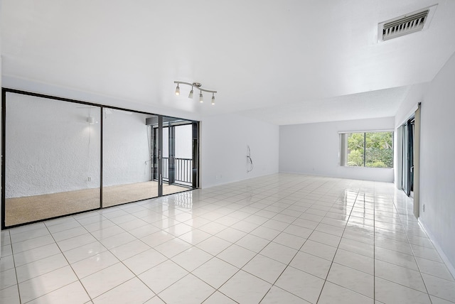 tiled empty room featuring rail lighting