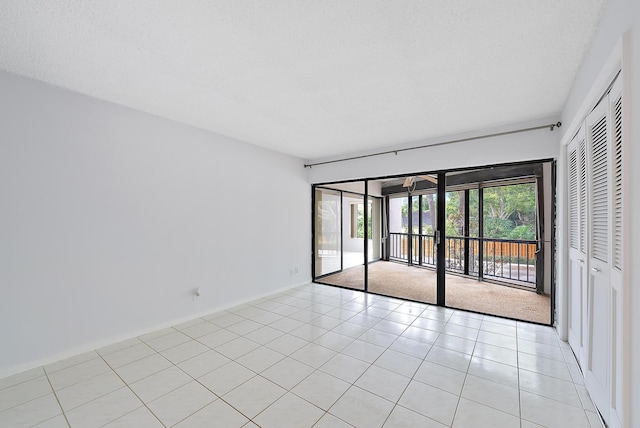 empty room featuring a textured ceiling and light tile patterned flooring