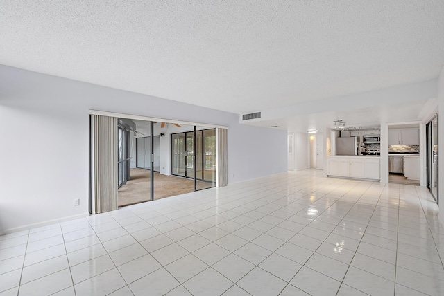 interior space with a textured ceiling, light tile patterned floors, and ceiling fan