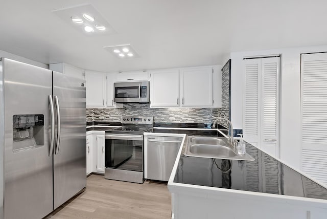 kitchen with white cabinetry, appliances with stainless steel finishes, sink, and light hardwood / wood-style floors