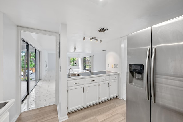 kitchen with sink, a healthy amount of sunlight, light hardwood / wood-style flooring, white cabinets, and stainless steel fridge