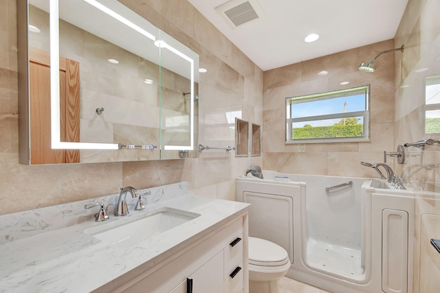 bathroom featuring tile walls, tiled shower, vanity, and toilet