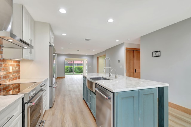 kitchen with light hardwood / wood-style flooring, sink, a kitchen island with sink, white cabinetry, and appliances with stainless steel finishes