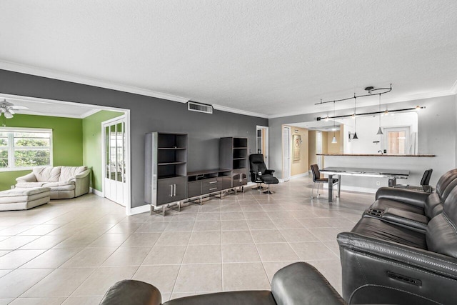 living room with a textured ceiling, ceiling fan, light tile patterned flooring, and crown molding