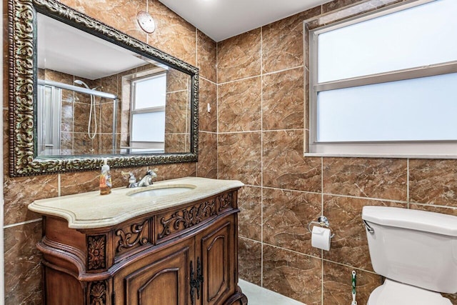 bathroom with vanity, toilet, tile walls, and walk in shower