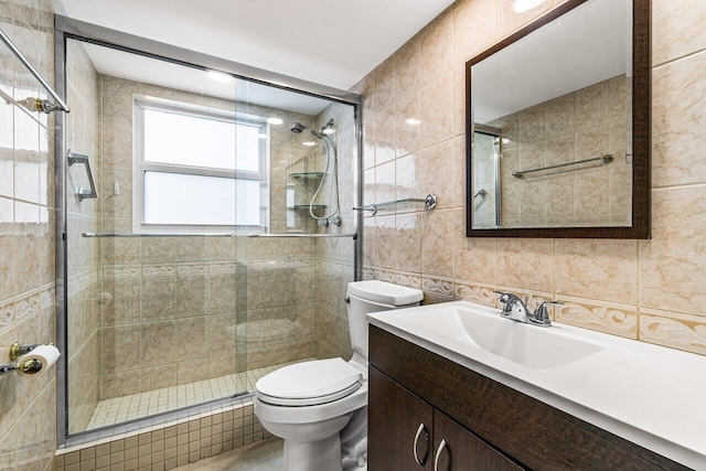 bathroom featuring backsplash, toilet, vanity, a shower with shower door, and tile walls