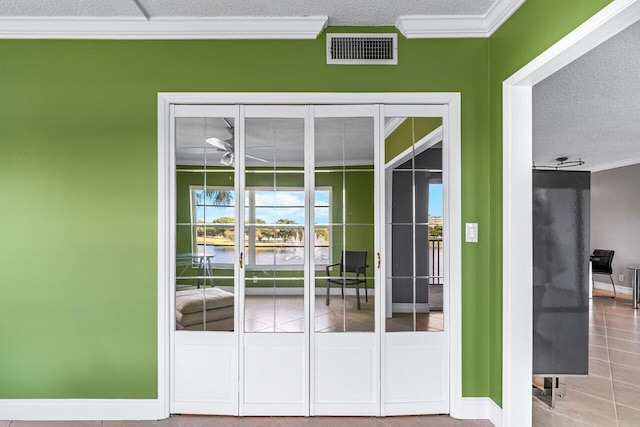 entryway featuring tile patterned flooring, ornamental molding, and a textured ceiling