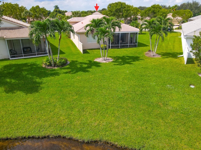 view of yard featuring a sunroom and a water view