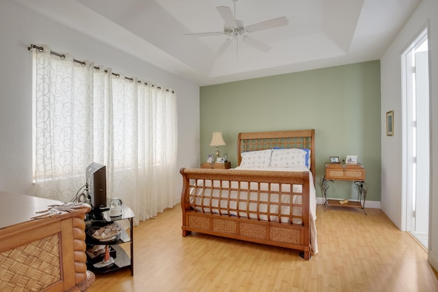 bedroom featuring hardwood / wood-style floors, ceiling fan, and a raised ceiling