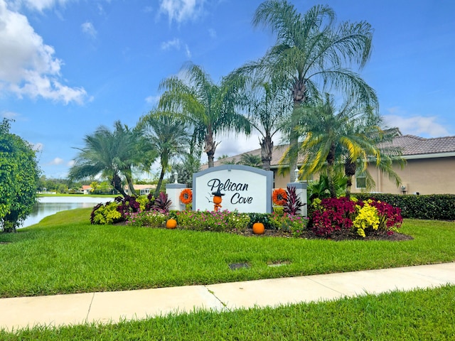 community sign with a water view and a yard