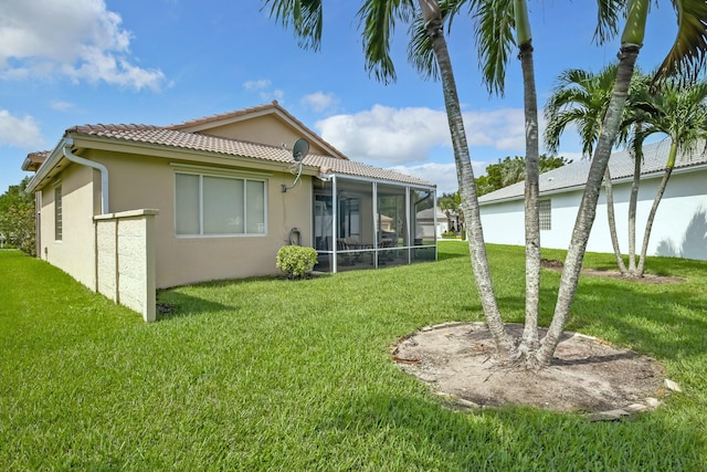 rear view of property featuring a sunroom and a lawn